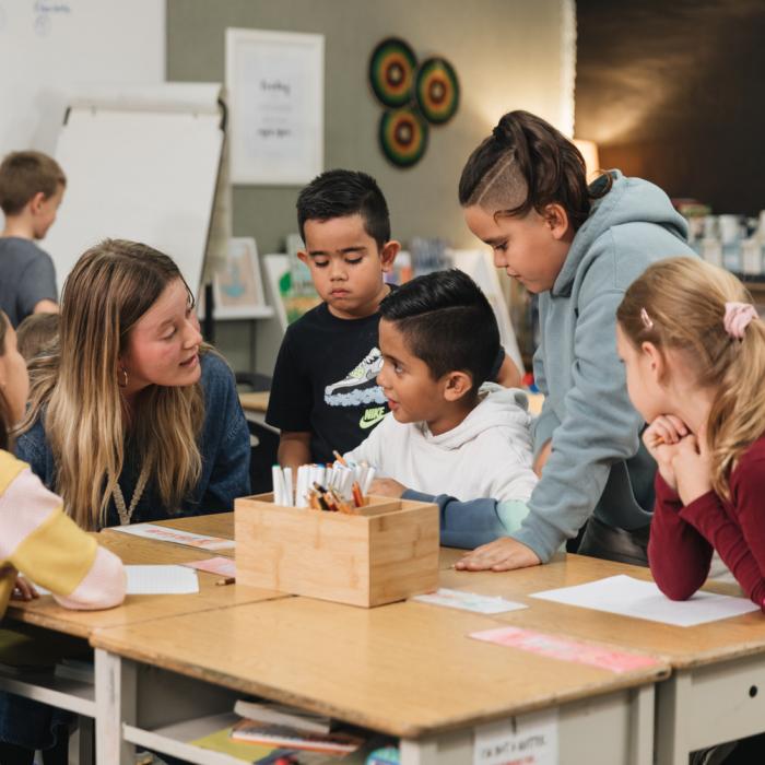 A teacher at a table surrounded by her students.
