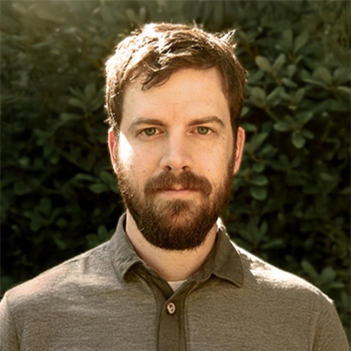 Andrew Klager standing in front of greenery