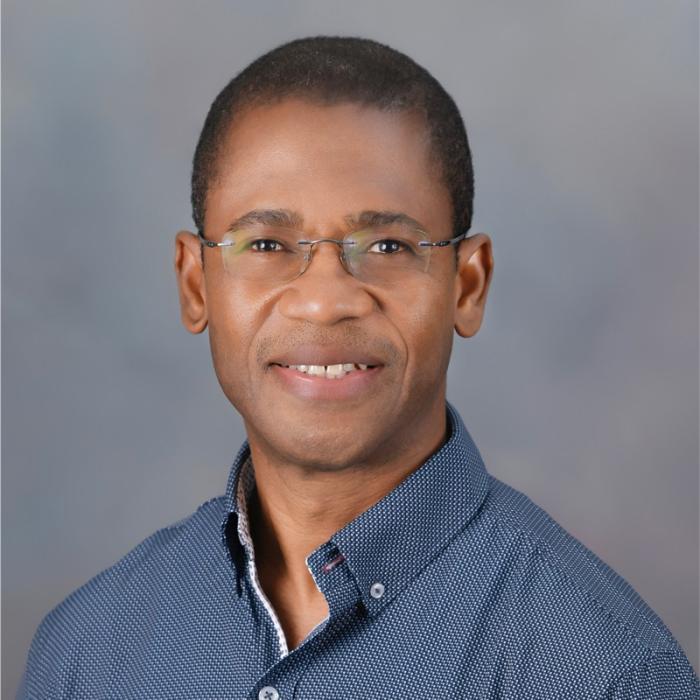 Divine Agodzo headshot in front of a grey wall