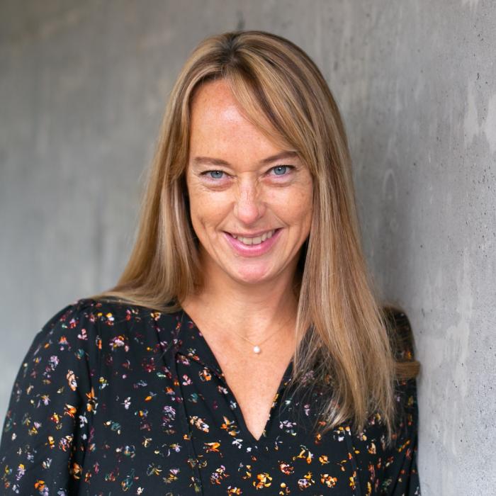 Kathy Holmes standing in front of grey wall