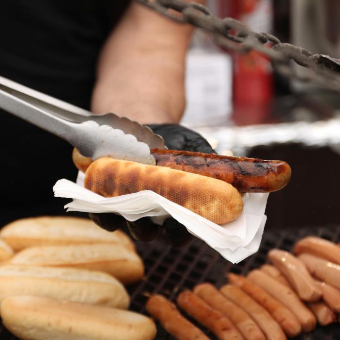 a hand holding a hotdog in a napkin