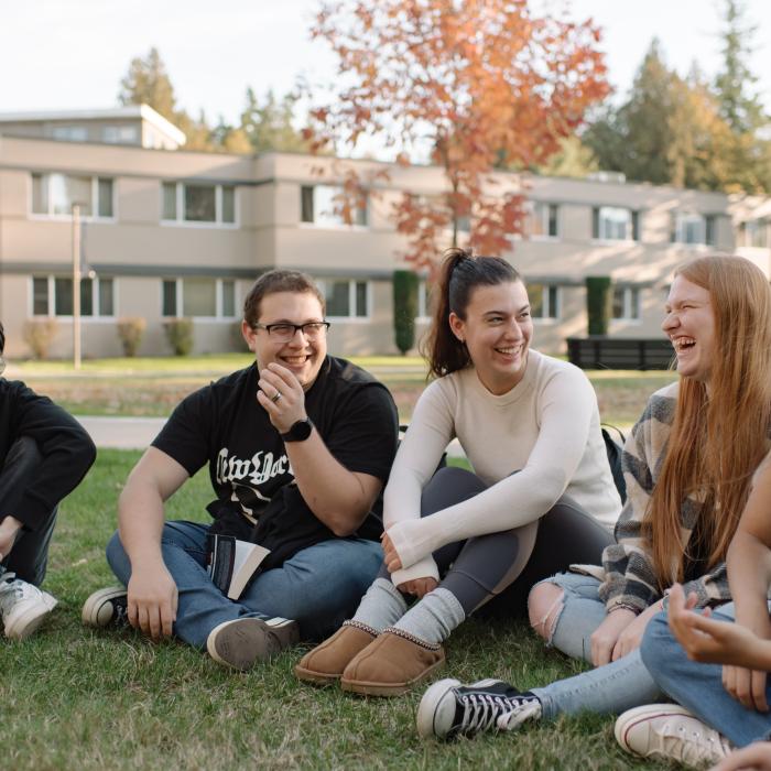 A group of people sit in a circle on the grass.