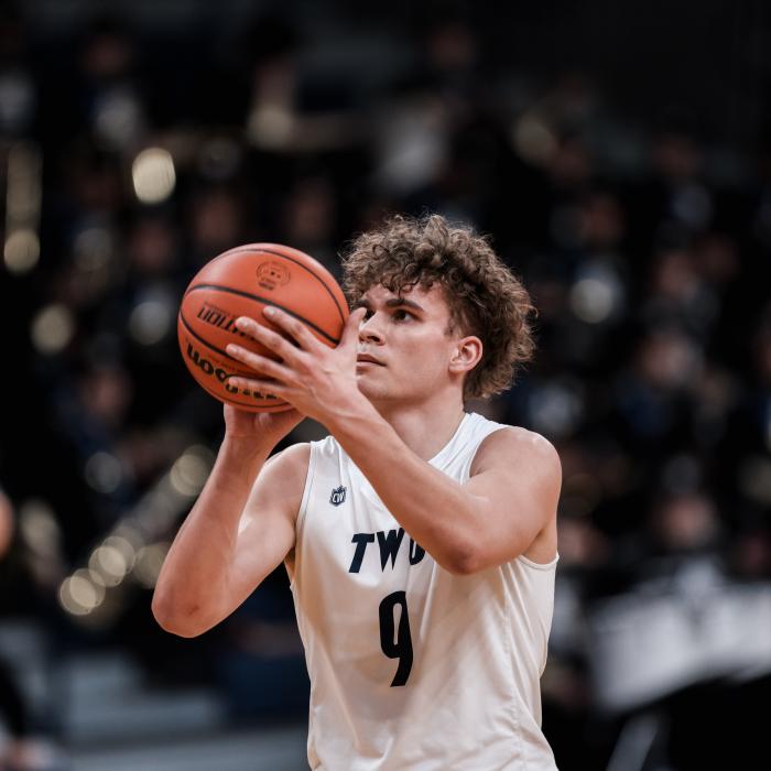 A basketball player in a white "TWU" jersey with number 9 prepares to shoot.