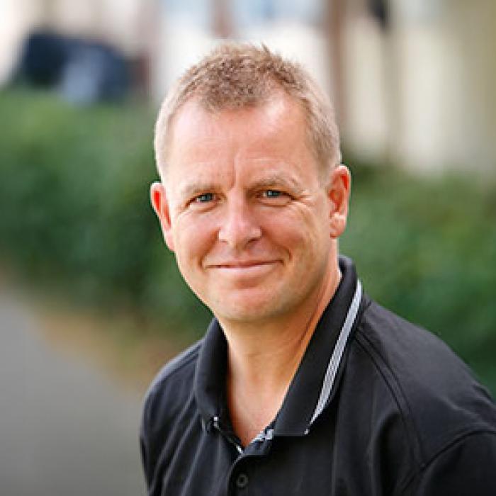 Neil Turner standing out side posing for a headshot