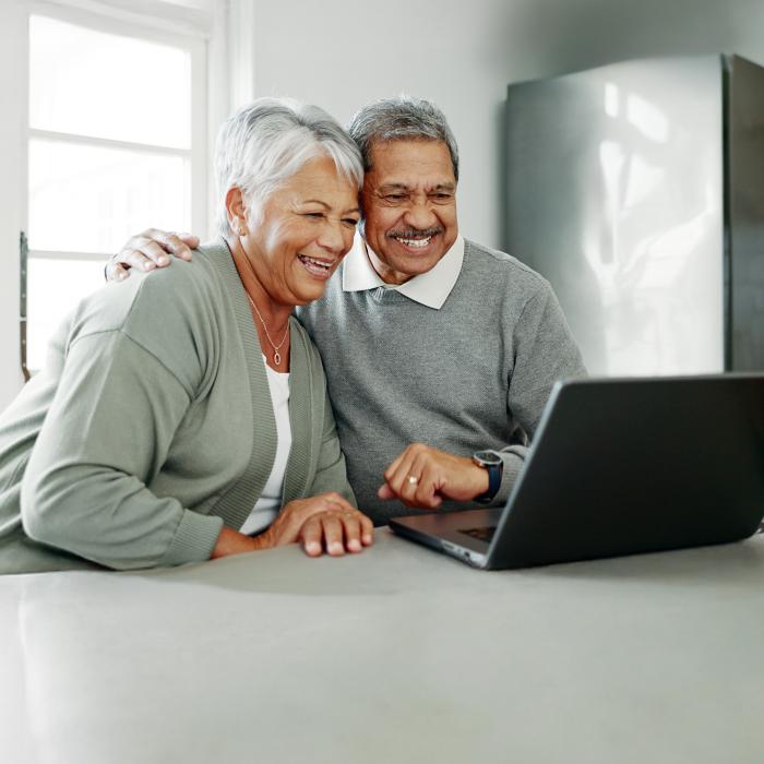 Elderly couple smiling and viewing laptop together at a table