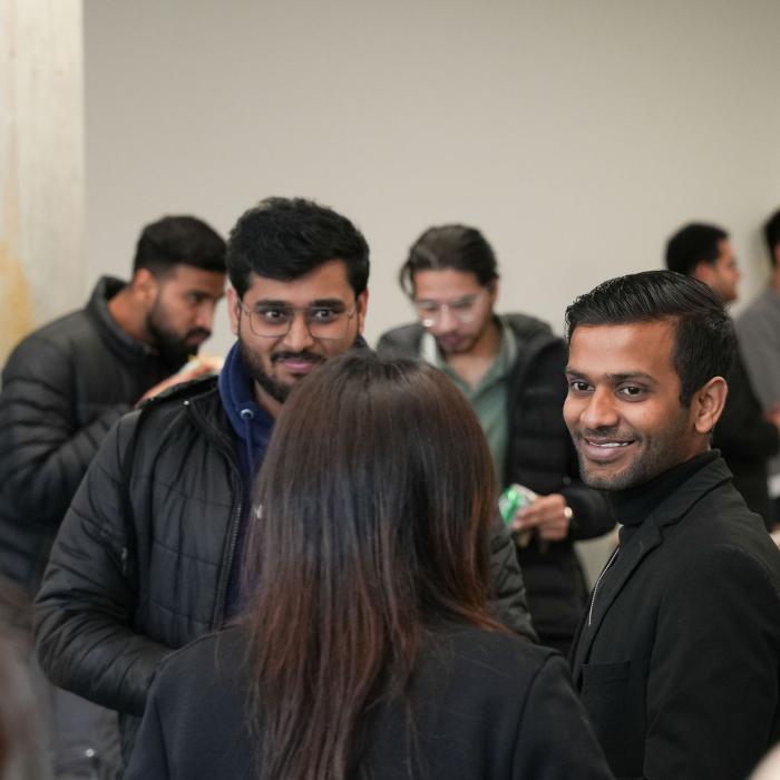 Group of people smiling and chatting in a hallway.