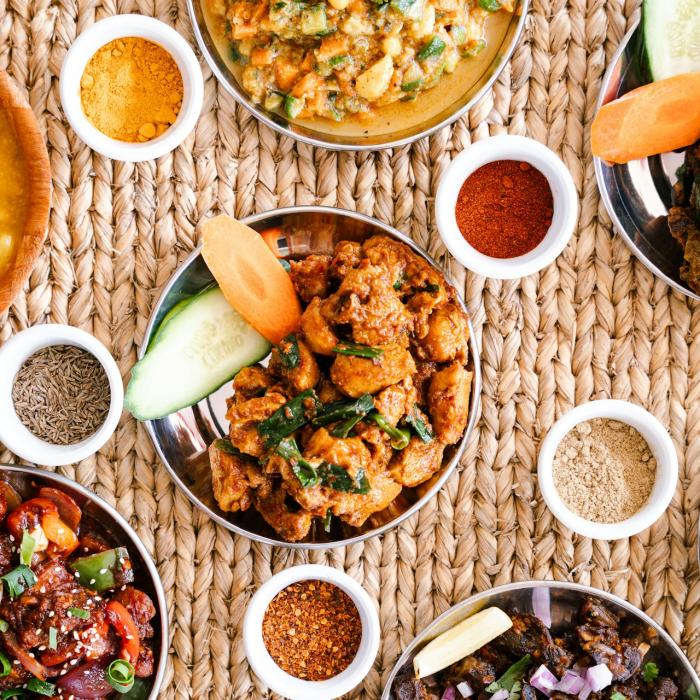 Assorted dishes on woven mat with small bowls of spices.