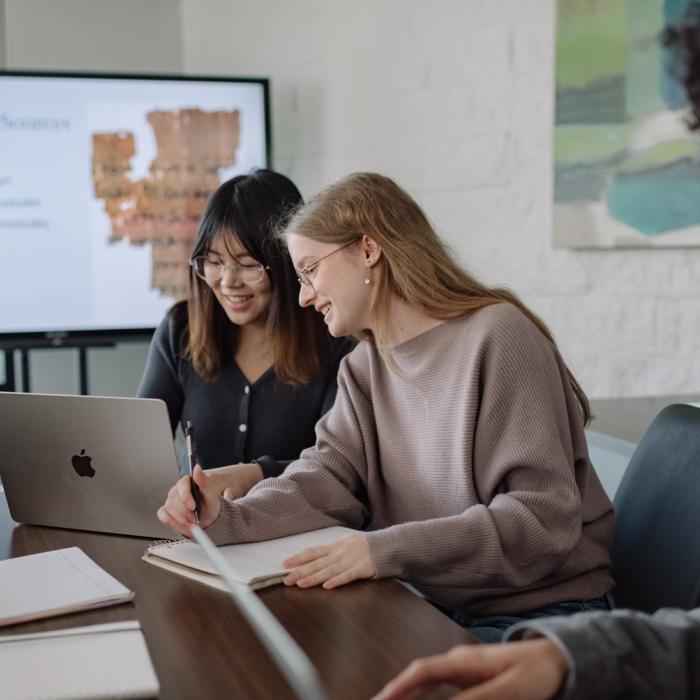 Group of people collaborating at a table with a laptop and papers.