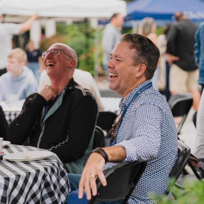 Men laughing together at an outdoor gathering.