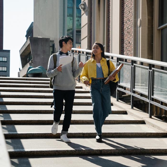 Stock photo of two people walking down outdoor steps, talking and smiling.