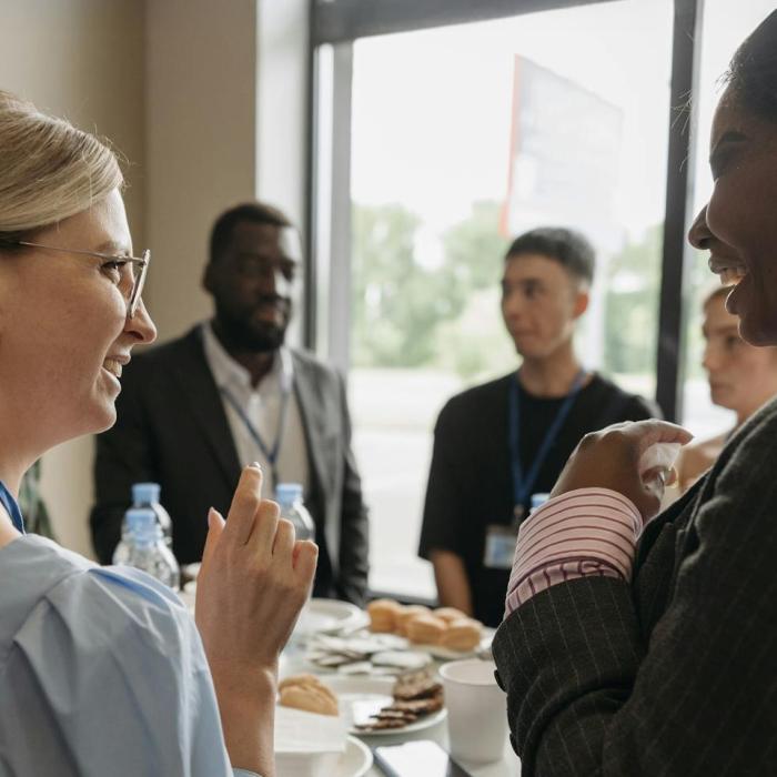 People in business attire chatting and smiling at a networking event.
