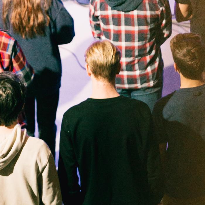 Crowd of people standing in a dimly lit room.