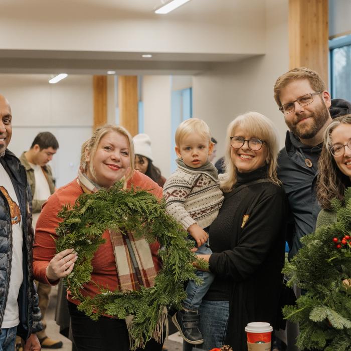 A family pose and smile at the camera, holding wreaths.