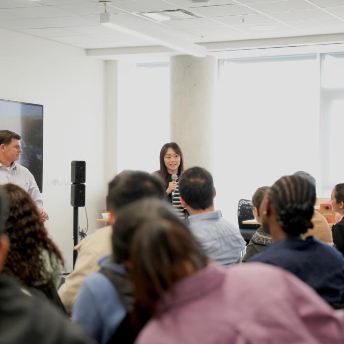 Woman speaks to a mid-size audience in a bright classroom
