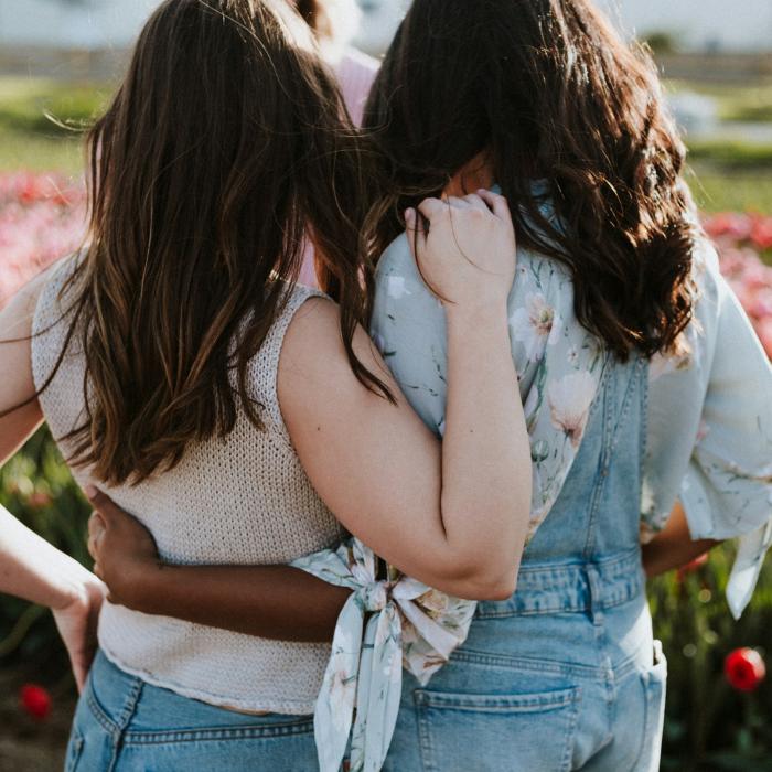 Two women embracing each other in a field of flowers.