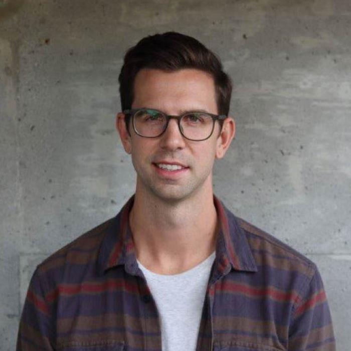 Derek Thiessen standing in front of a grey wall