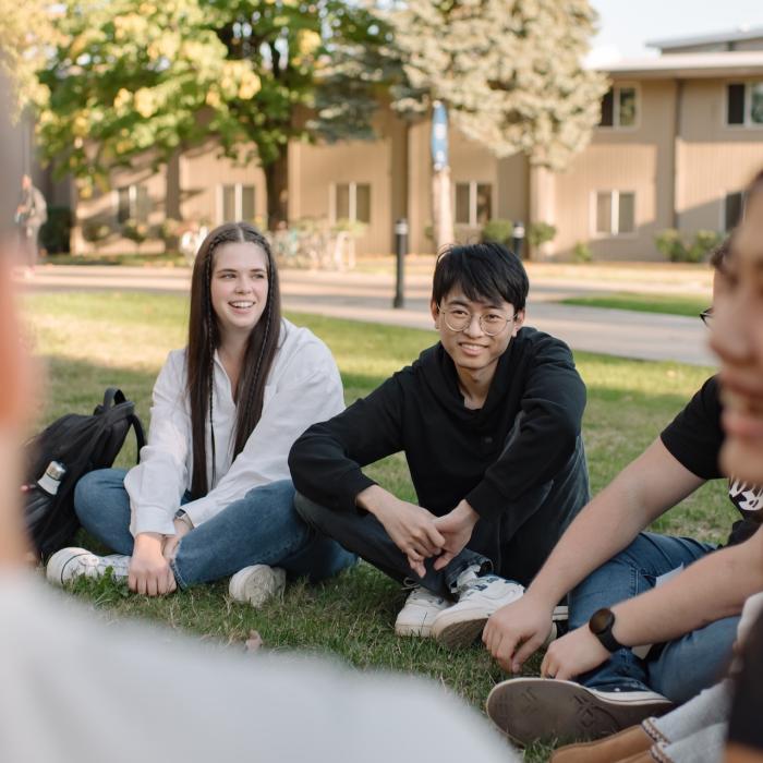 group of students sitting outside on the grass