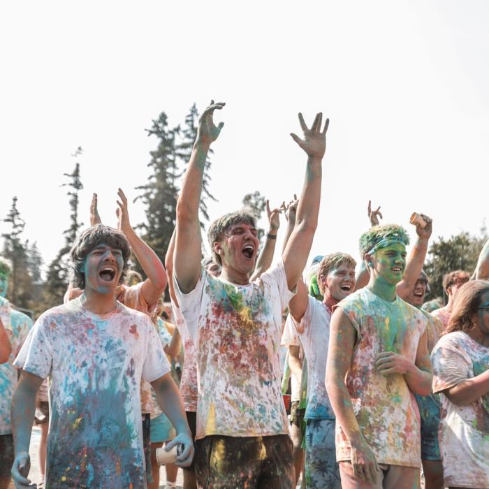 group of people covered with coloured chalk cheering