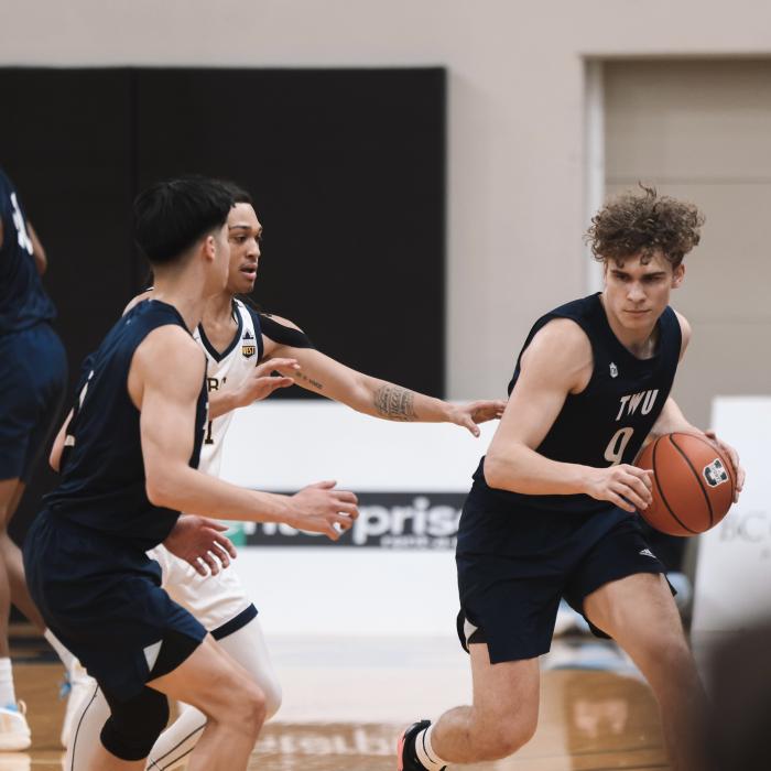 Basketball players in black and white jerseys compete on the court.