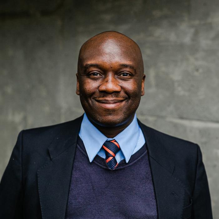 Christopher Ogundare standing in front of grey wall