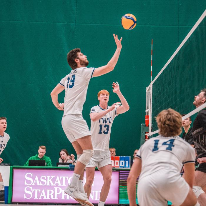 Men in white jersey playing volleyball in a court