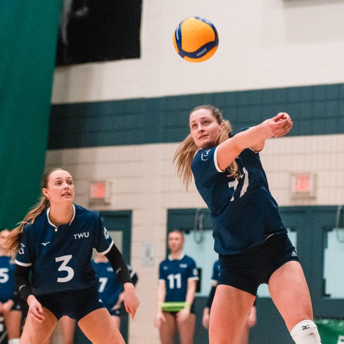 Women in blue jersey playing volleyball