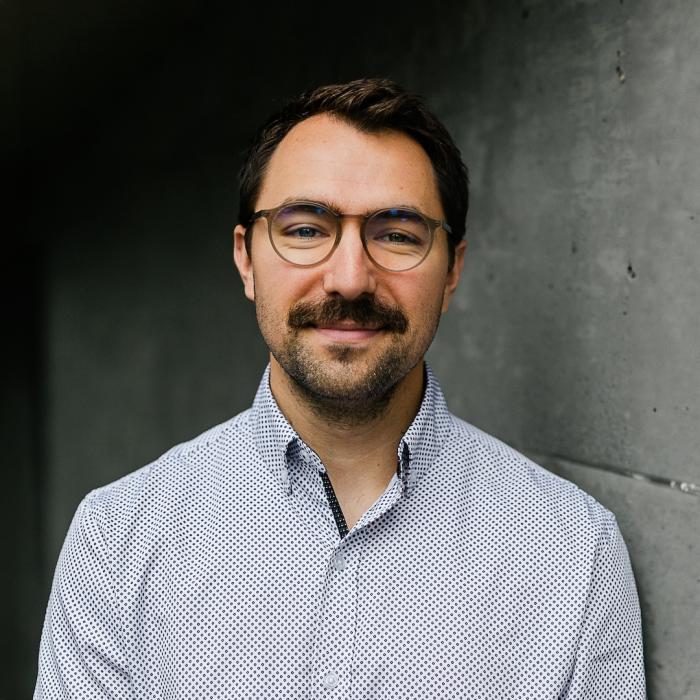 Headshot of Spencer Epp against a dark concrete wall.