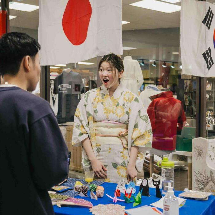 Students engaging at a cultural booth decorated with international flags during a TWU Culture Week event.